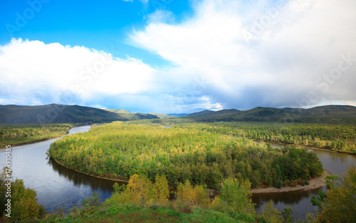 beautiful autumn landscape with curving river and forest under blue sky