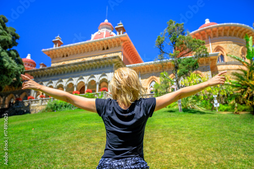 Carefree blonde caucasian woman with open arms at arabesque Monserrate Palace and botanical garden in a beautiful sunny day. Female tourist enjoys in famous landmark in Sintra, Lisbon, Portugal.