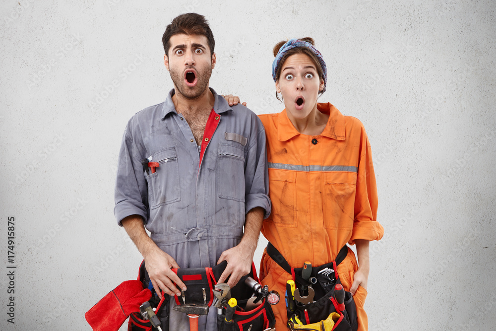 Portrait of shocked electricians stare at camera, look with bugged eyes
