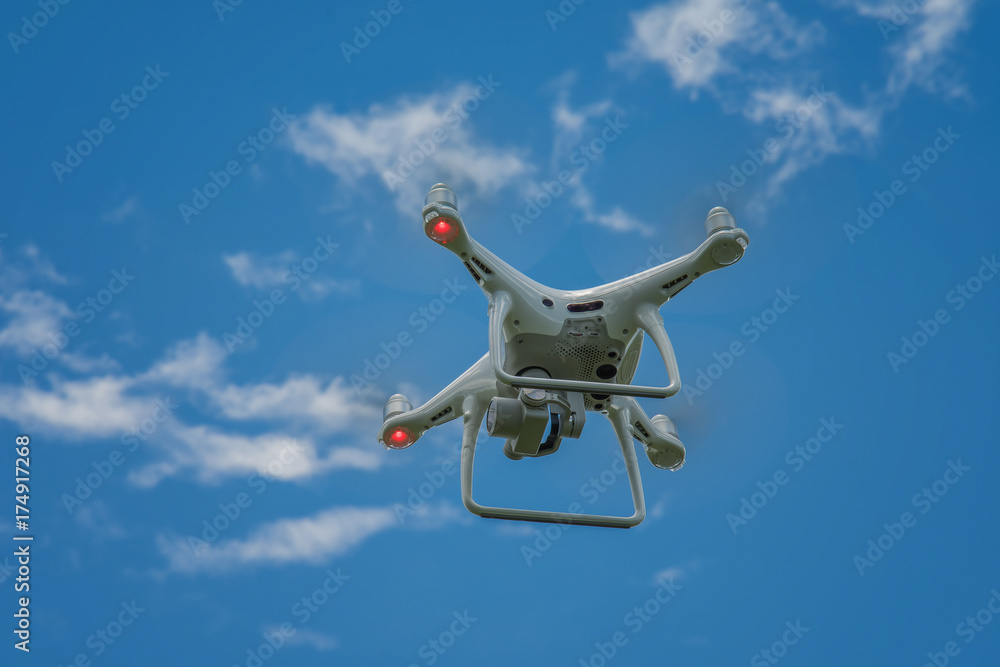 white drone hovering in a bright blue sky white drone hovering in a bright blue sky