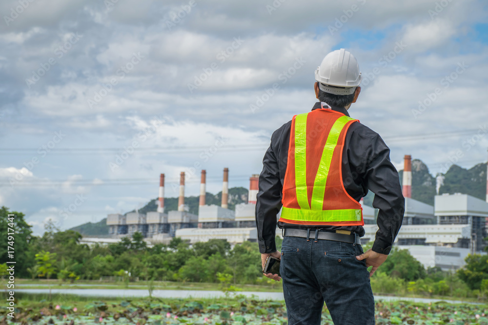 Engineer with a coal power plant in the background. Engineer with a coal power plant in the background.