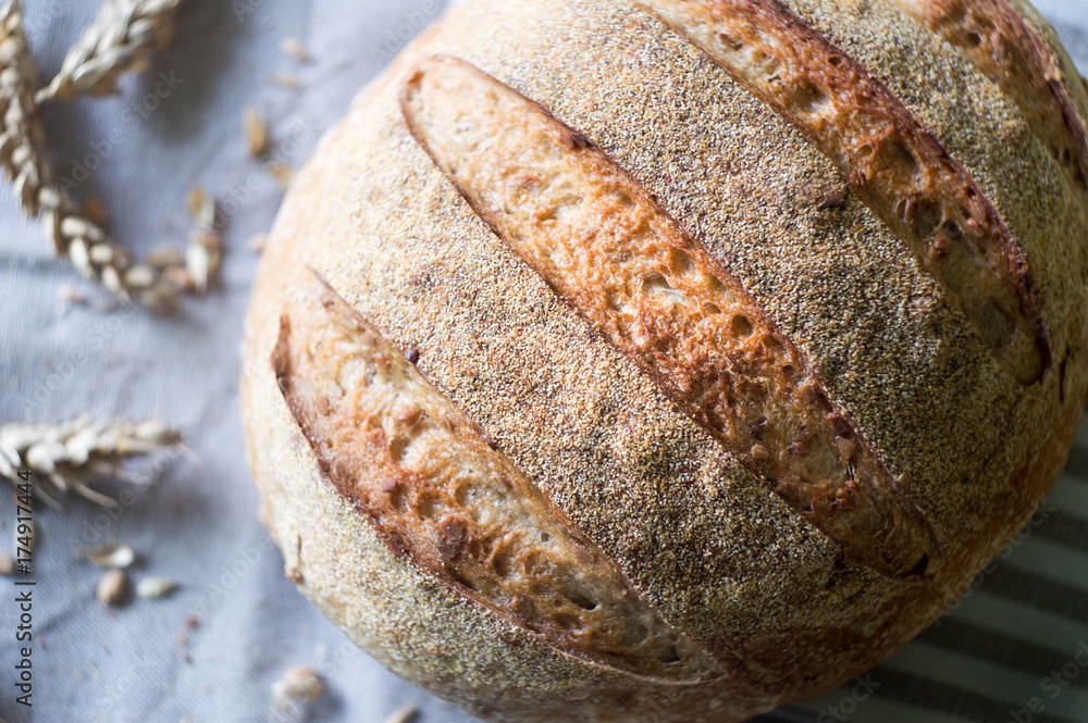 Φωτογραφία Close-up of whole wheat sourdough bread and ears of wheat on a kitchen towel