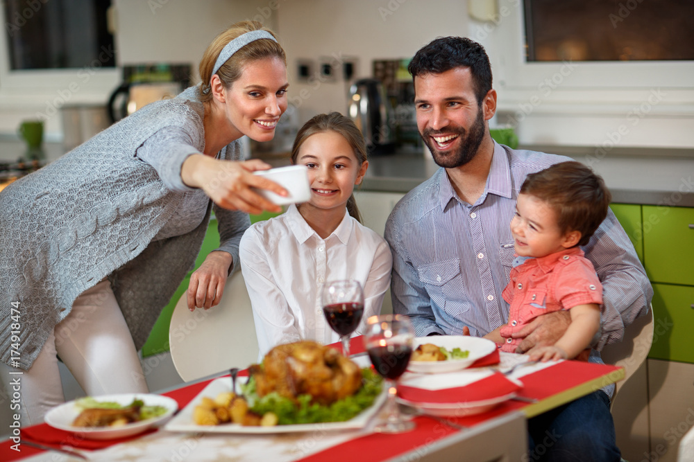 Family with children making Christmas selfie at the set table