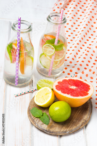 Infused flavored water with fresh fruits on white wooden background.Refreshing summer homemade detox water