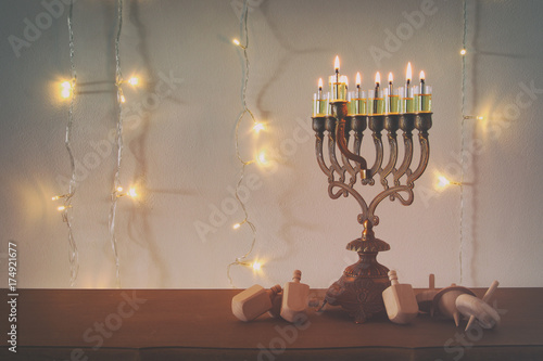 Fototapeta Naklejka Na Ścianę i Meble -  Low key image of jewish holiday Hanukkah background with traditional spinnig top, menorah (traditional candelabra)