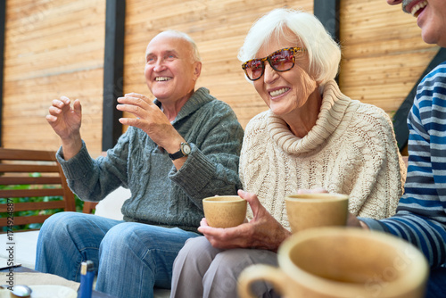 Canvas Print Cheerful senior friends gathered together at cozy small patio and remembering fu