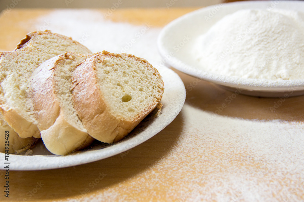 Slices of bread and wheat flour in a white plate on the table