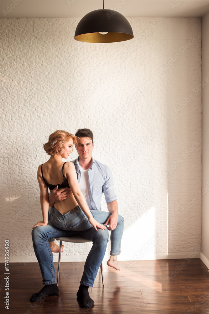 couple being intimate sitting down on chair, while the man undoing woman's  bra. Stock Photo | Adobe Stock