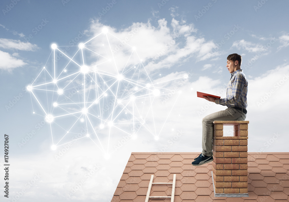 Man on brick roof reading book and concept of social connection Man on brick roof reading book and concept of social connection
