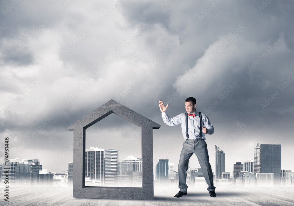 Manager man crashing stone home as symbol for real estate insura Manager man crashing stone home as symbol for real estate insura