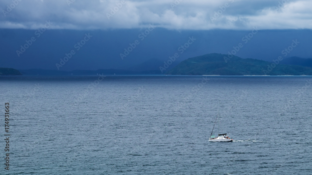 Boat at the sea with storm clouds and rain over sea on background.