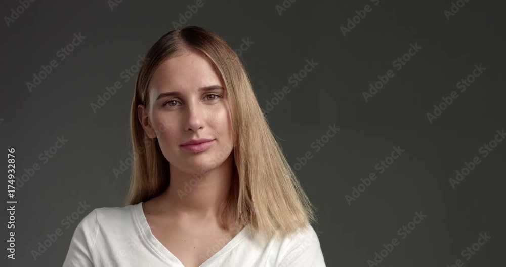 Pretty flirty blond girl in a white top isolated on dark gray trying on glasses and playing with camera Pretty flirty blond girl in a white top isolated on dark gray trying on glasses and playing with camera