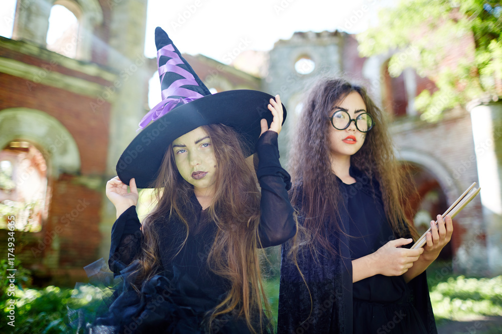 Two spooky girls in witch costumes on background of ruined castle Two spooky girls in witch costumes on background of ruined castle