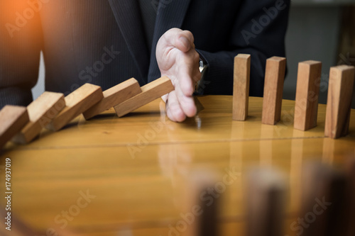 businessman hand stop dominoes continuous toppled or risk with copyspace. photo