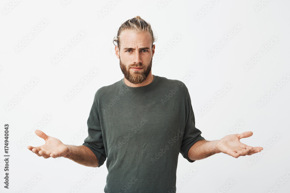 Handsome nordic man with beard and stylish hairdo spreads hands with cynical and mean expression when somebody pushed him on street. Handsome nordic man with beard and stylish hairdo spreads hands with cynical and mean expression when somebody pushed him on street.