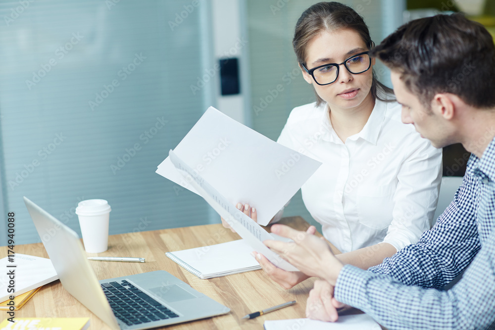 Contemporary accountants discussing papers with financial data at meeting Contemporary accountants discussing papers with financial data at meeting