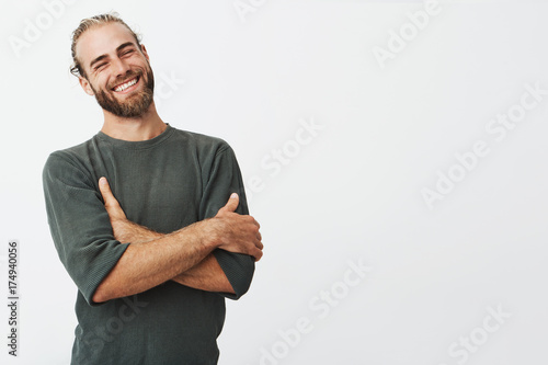Tela Attractive swedish man with stylish hair and beard laughs at funny story from friend with crossed hands and closed eyes