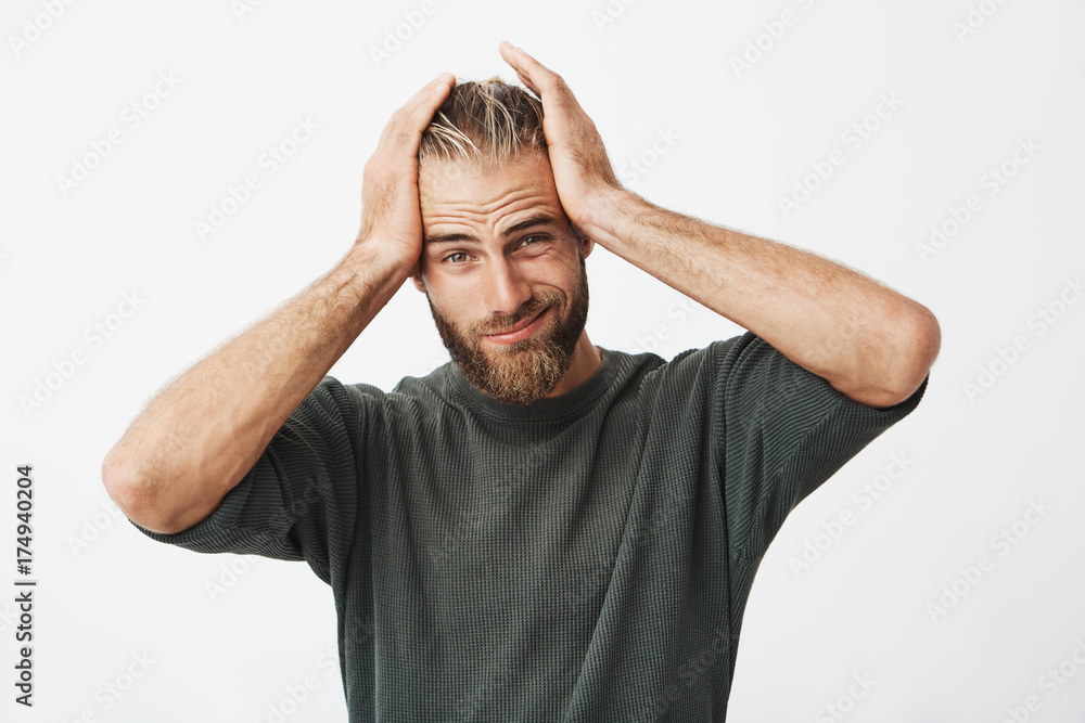Fototapeta premium Portrait of handsome man with stylish hairstyle and beard having tired expression because of headache after hard day on work.