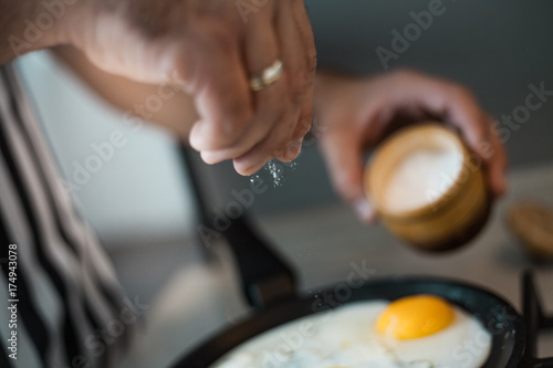 A man cook in a beautiful striped apron prepares and salt eggs in a beautiful kitchen