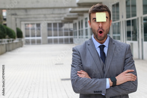 Surprised businessman with a note on his forehead with copy space 