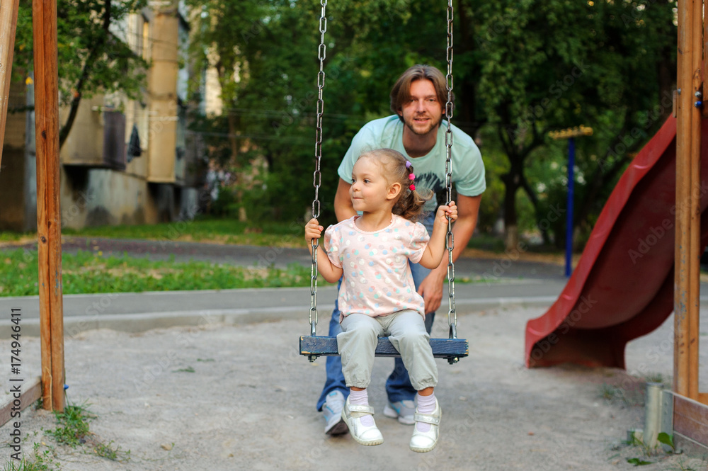 A girl with a dad on the playground on a swing A girl with a dad on the playground on a swing