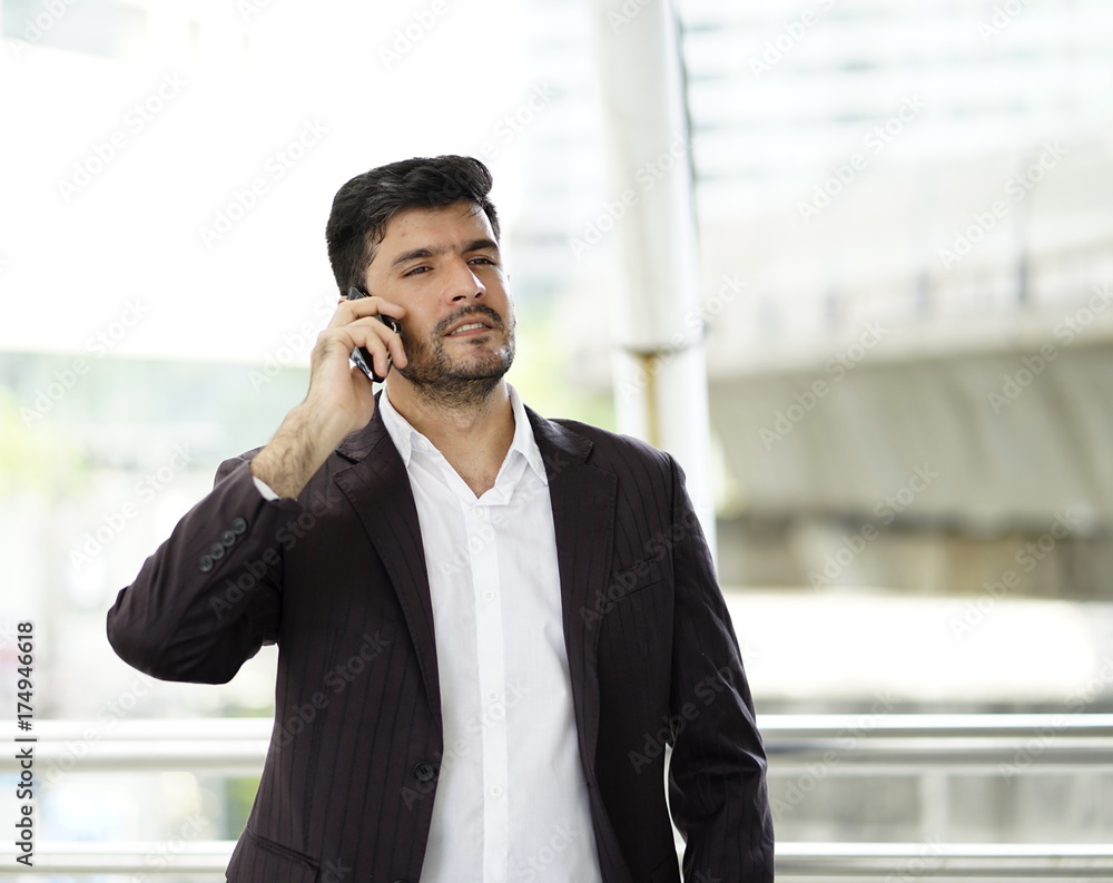 Middle east business man on call and holding smartphone between business trips. Middle east business man on call and holding smartphone between business trips.