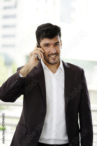 Middle east business man on call  and holding smartphone between business trips.
