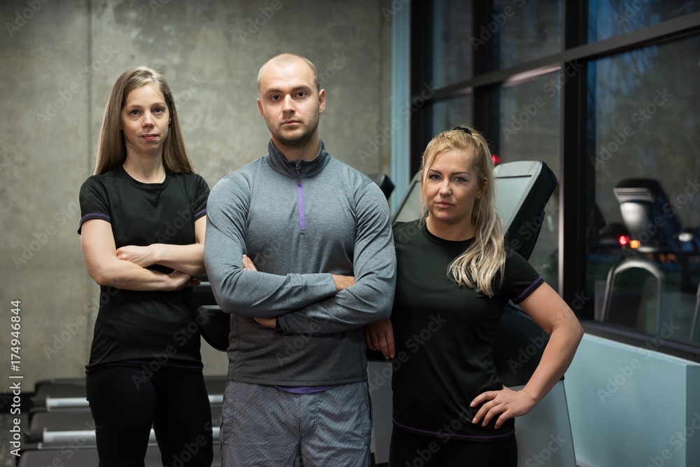 Portrait of friends standing against treadmills