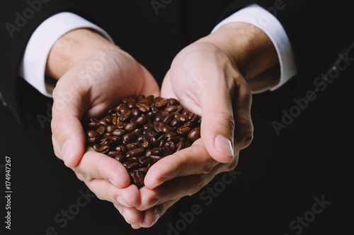 Coffee beans in hands on white background