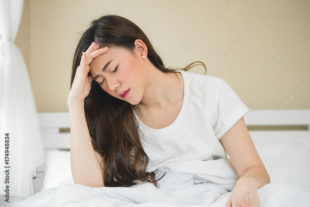 Asian woman have a headache in bedroom morning because sleep problem Asian woman have a headache in bedroom morning because sleep problem