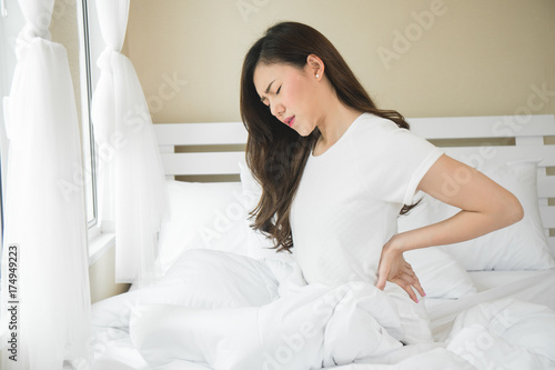 Asian woman have a backache in bedroom morning because sleep problem