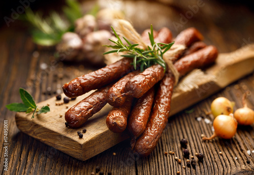 Kabanosy, polish sausages made of pork on a board with addition of fresh herbs and spices