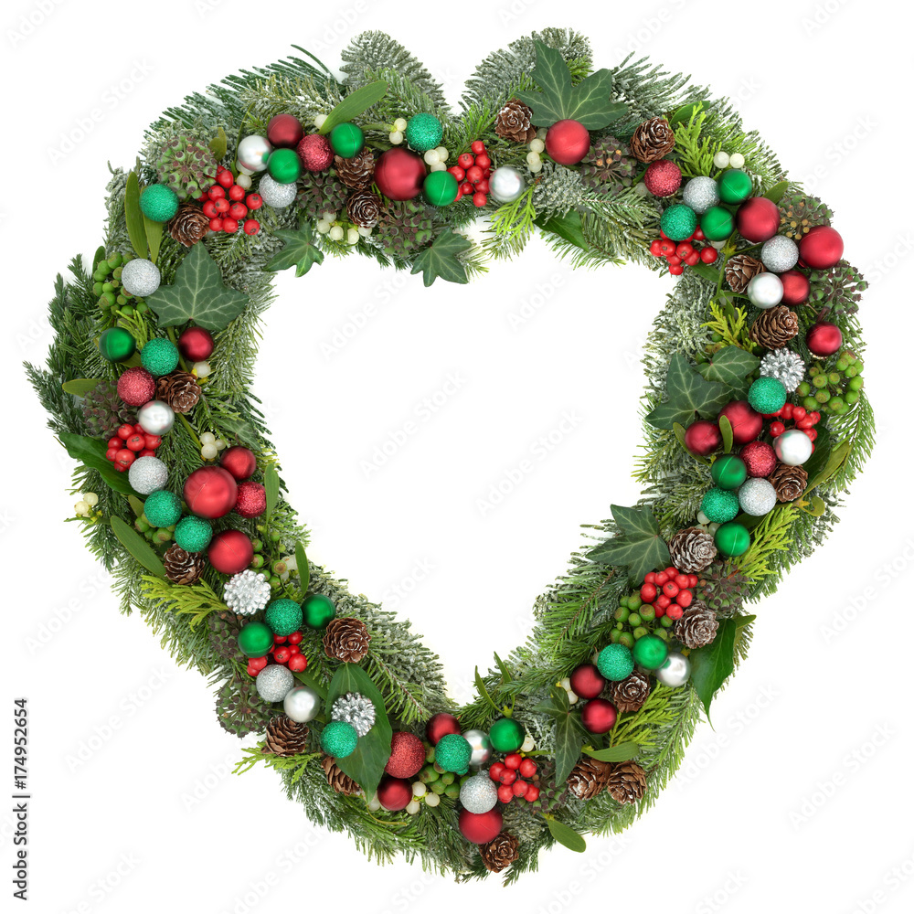 Christmas heart shaped wreath decoration with red, green and silver bauble decorations, mistletoe, fir, blue spruce, cedar, pine cones and ivy leaves on white background.