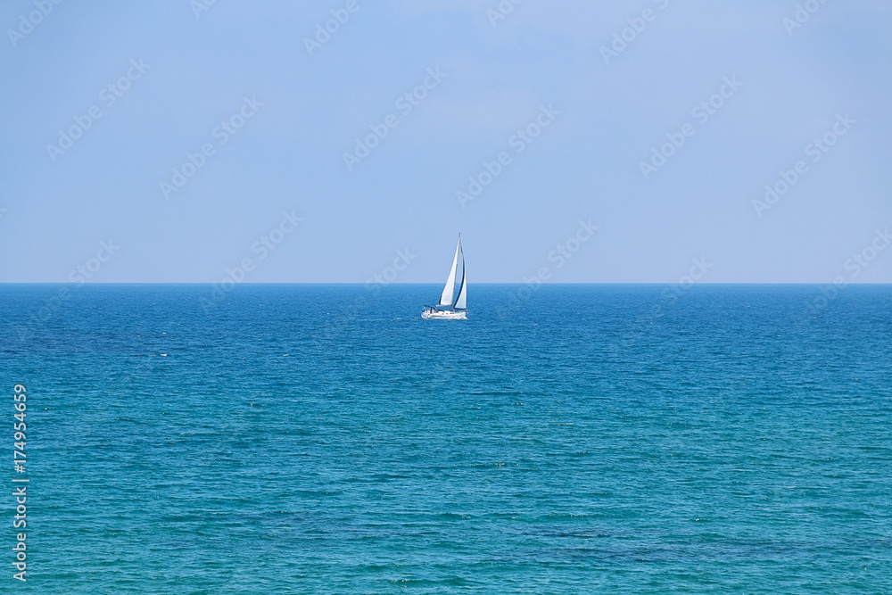 White sailboat floating on a calm sea.