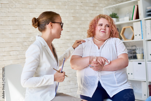 Fototapeta Naklejka Na Ścianę i Meble -  Portrait of  young woman  comforting  crying obese woman during therapy session on mental issues