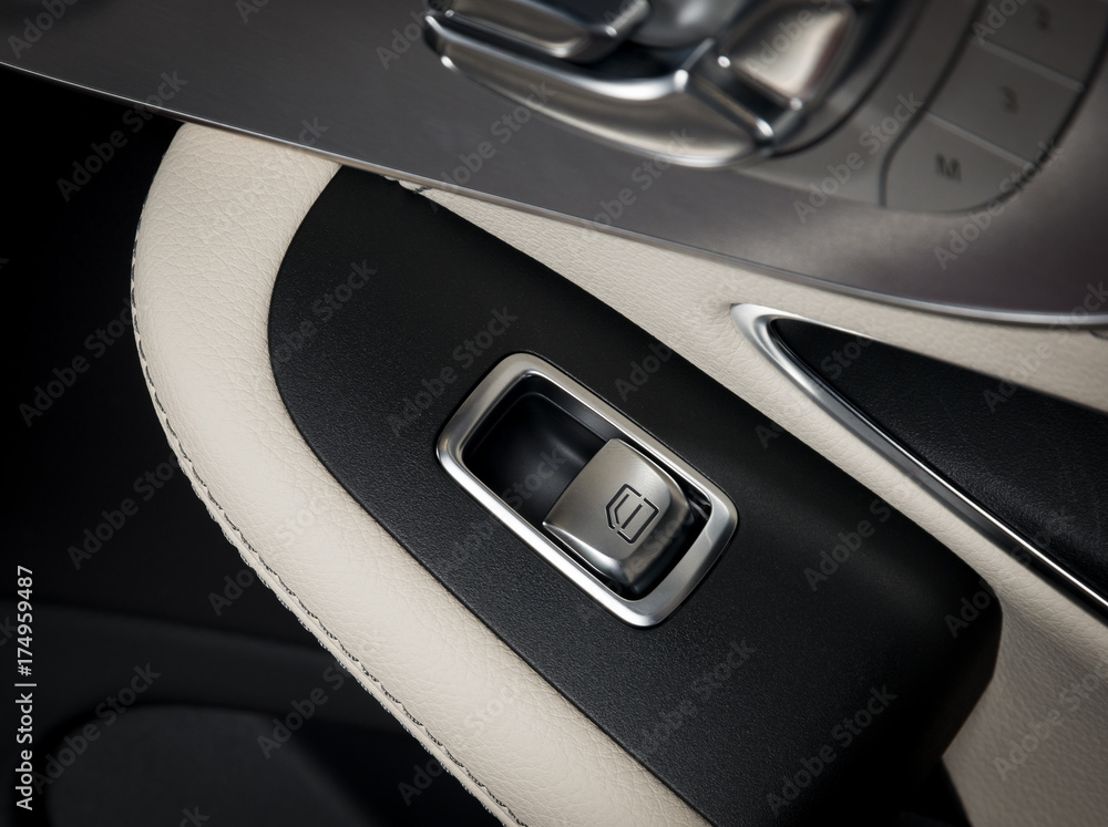 Door handle with windows control buttons of a luxury passenger car. White leather interior of the luxury modern car. Modern car interior details