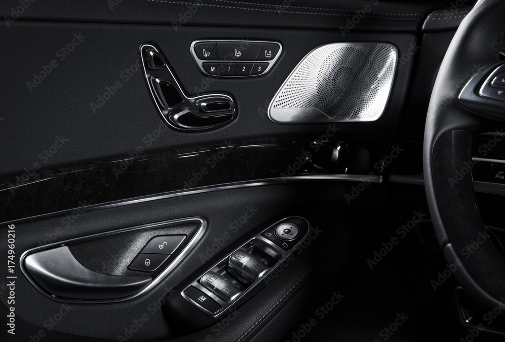 Door handle with Power seat control buttons of a luxury passenger car. Black leather interior of the luxury modern car. Modern car interior details