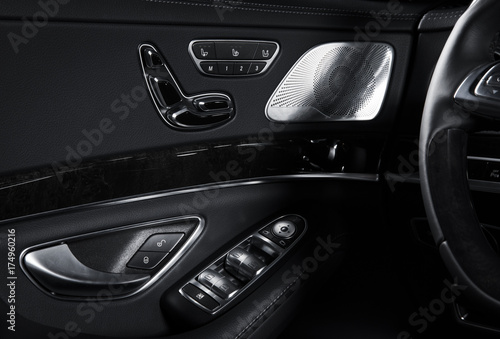 Door handle with Power seat control buttons of a luxury passenger car. Black leather interior of the luxury modern car. Modern car interior details