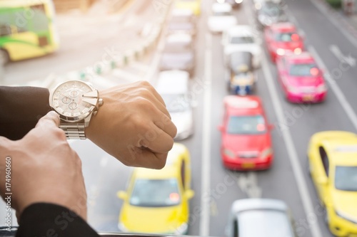 Canvas Print young businessman looks at the watch on the road in rush hour.