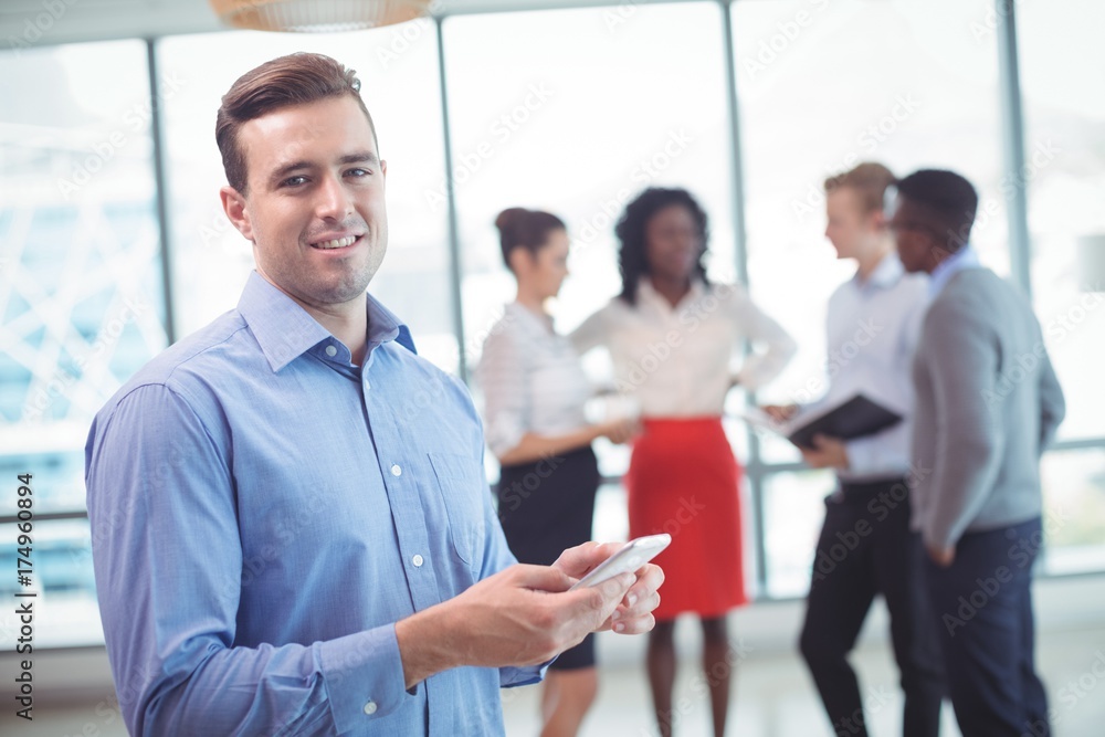 Smiling businessman using mobile phone with colleagues Smiling businessman using mobile phone with colleagues