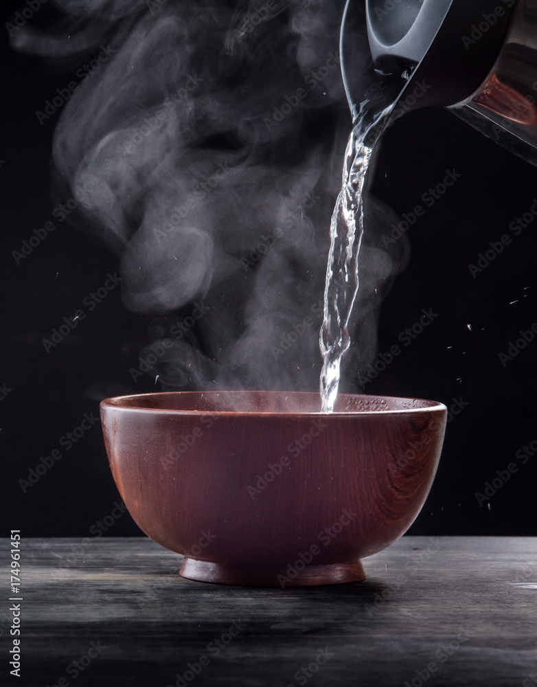 Pouring hot water into into a bowl on a black background Stock Photo |  Adobe Stock