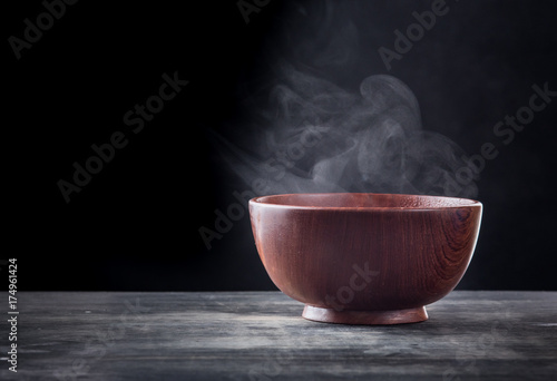 Steam of hot soup in a soup bowl with smoke on black background