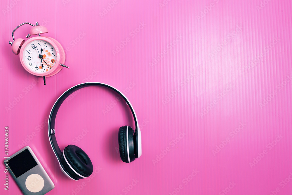 wireless headphones and media player, pink alarm clock on pink paper  background. Stock Photo | Adobe Stock