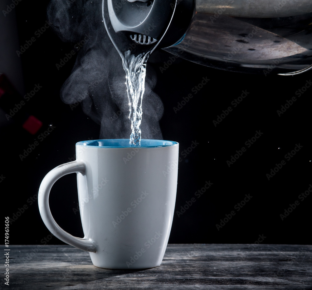 Pouring hot water into into a cup on a black background Stock Photo