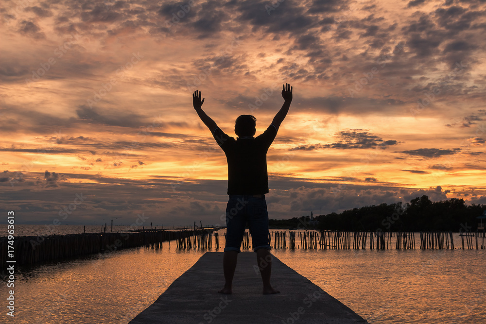man with raised-up arms at the beautiful sunset
