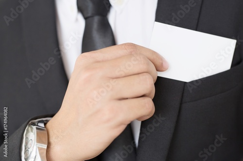 Young businessman who takes out blank business card from the pocket of his shirt business suit, copy space 