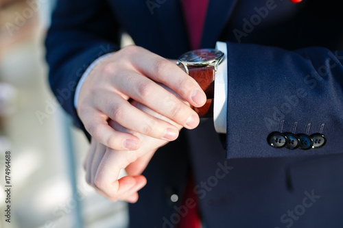 A young man in an expensive suit looking at his clock. Businessman looking at his watch.