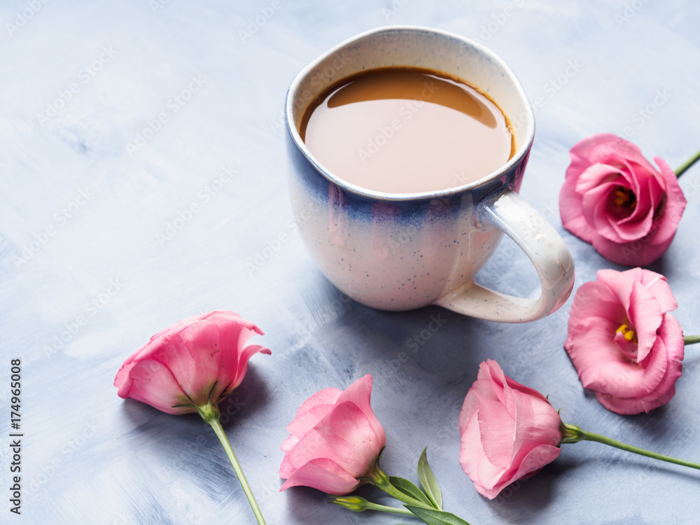 Mug of coffee and pink flowers on blue background. Festive mother valentine day greeting card Mug of coffee and pink flowers on blue background. Festive mother valentine day greeting card