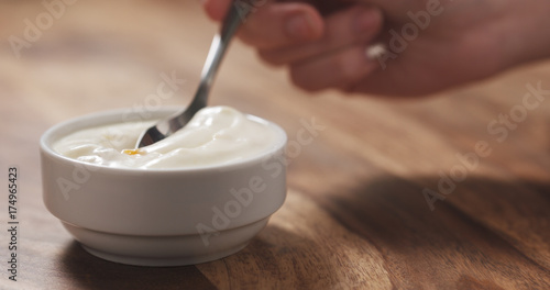 young female hand eating peach yogurt with spoon