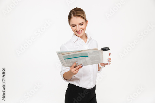 Smiling blonde business woman reading newspaper